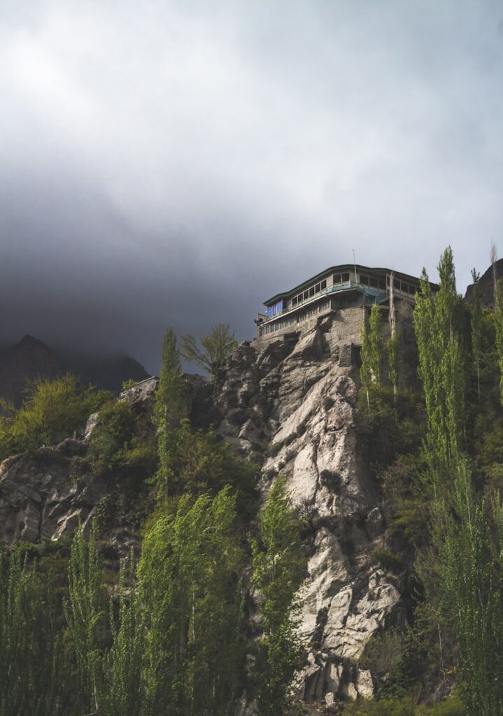 a house on top of a mountain surrounded by trees in hunza
