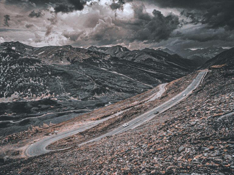 a car driving down a mountain road under a cloudy sky