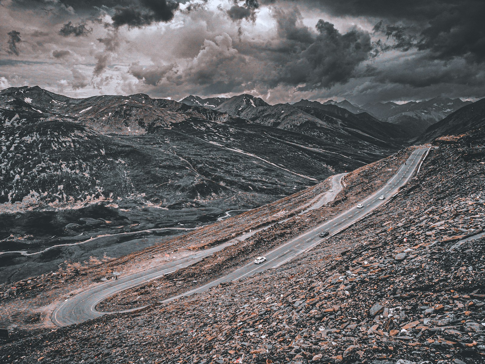 a car driving down a mountain road under a cloudy sky